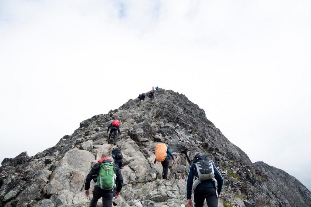 Trekkers in backpacks climb to the top of Besseggen, Norway